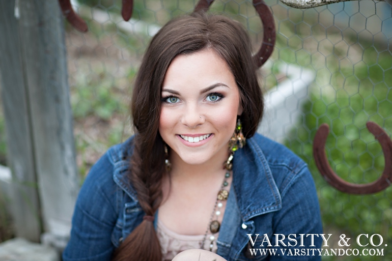 girl against a wire fence with horseshoes senior picture