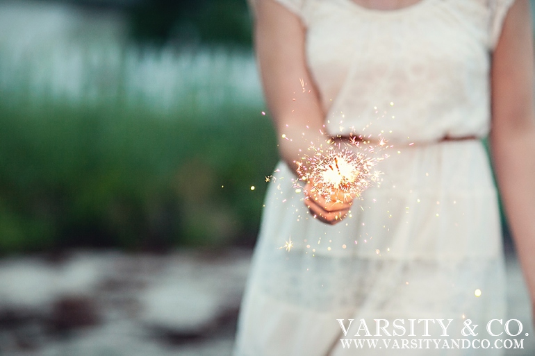 girl holding a sparkler on the beach senior picture