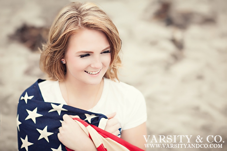 girl wrapped in the american flag on the beach senior picture