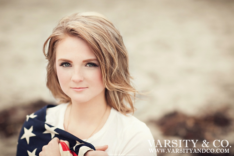 girl wrapped in the american flag on the beach senior picture